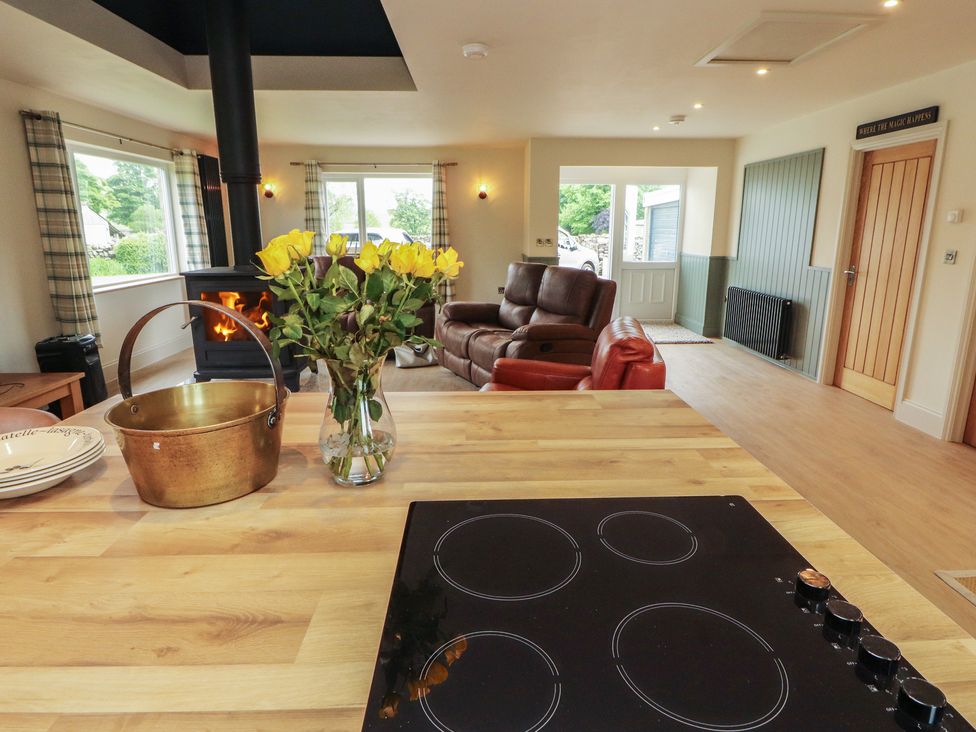 A kitchen with a stove and flowers on the table at Beckdale Settle