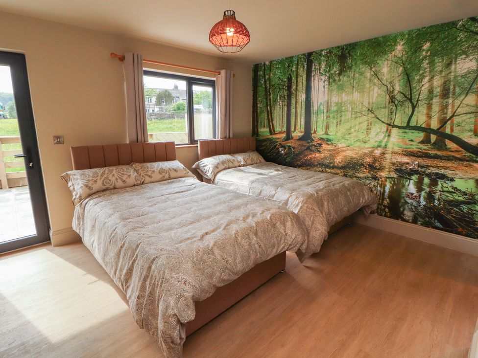 A bedroom with two beds and a mural of a forest at Beckdale in Settle