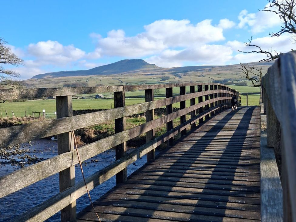 A bridge over a river with a mountain in the background at Beckdale in Horton-in-Ribblesdale near Settle