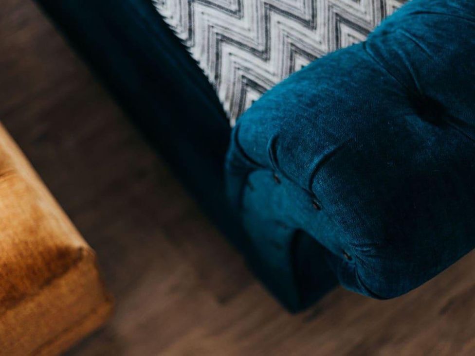 A sofa with a patterned cushion and wooden flooring at Cottage, 3 Bed, Sleeps 7, Free Parking
