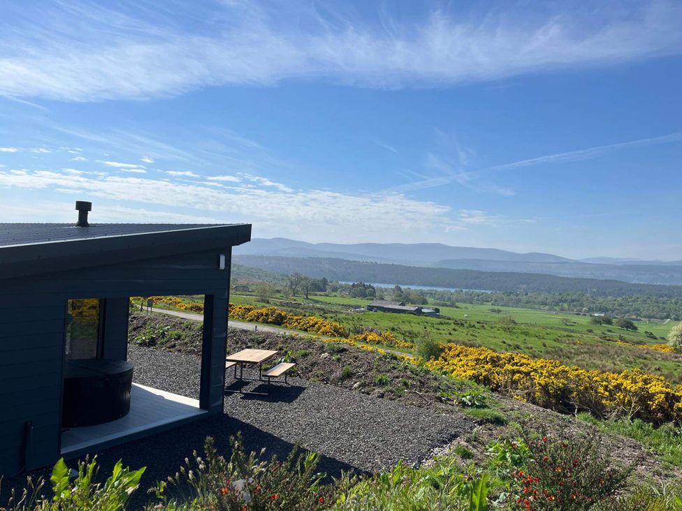 An outdoor area with a cabin and a hot tub at Migdale Heights - Luxury Cabins in The Highlands