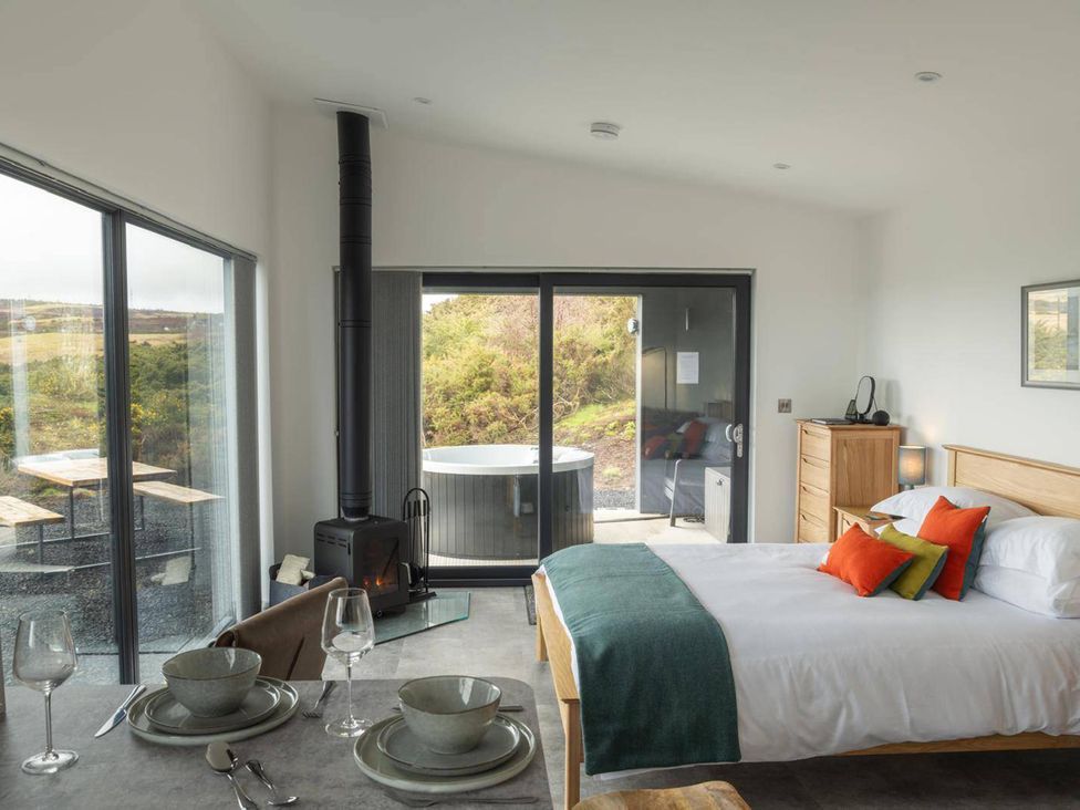 A bedroom with a bed and a dining set at Migdale Heights - Luxury Cabins in The Highlands