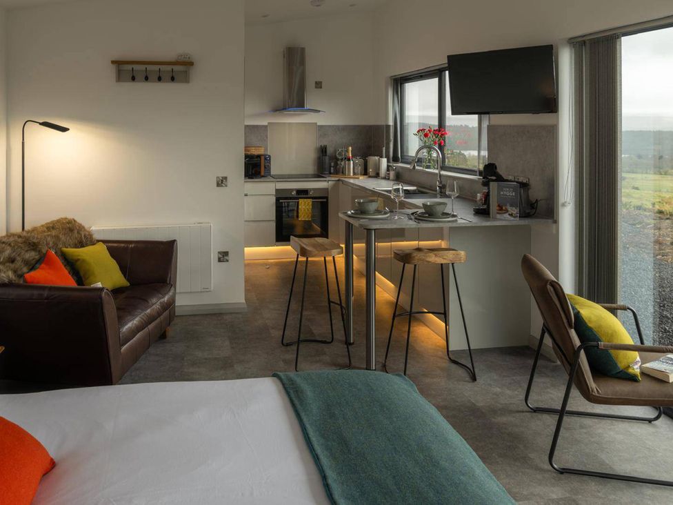A kitchen with stools and a sofa at Migdale Heights - Luxury Cabins in The Highlands