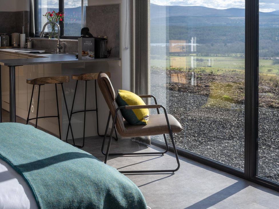A bedroom with a kitchen area featuring a bar counter and a view at Migdale Heights - Luxury Cabins in The Highlands