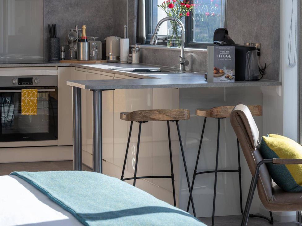 A kitchen with a sink, oven, and bar stools at Migdale Heights - Luxury Cabins in The Highlands