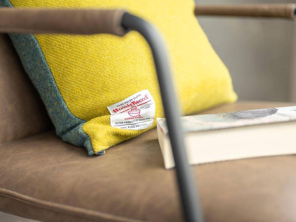 A chair with a yellow cushion and a book at Migdale Heights - Luxury Cabins in The Highlands
