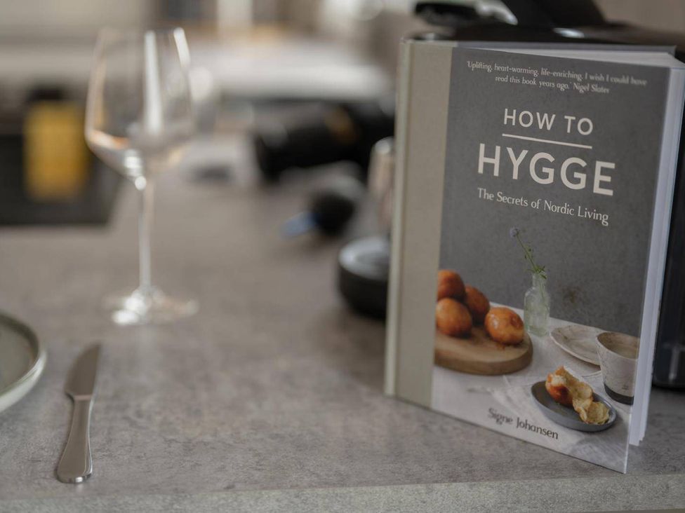 A kitchen with a book and a wine glass on the counter at Migdale Heights - Luxury Cabins in The Highlands