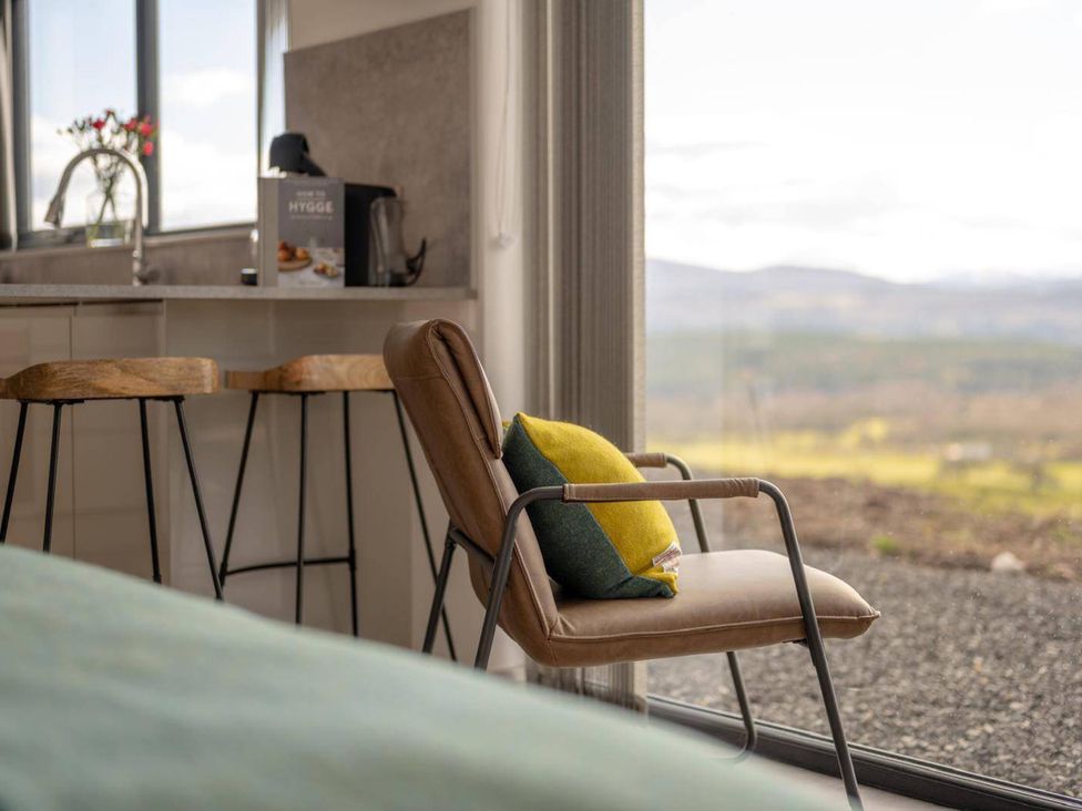 A living room with a chair and a view at Migdale Heights - Luxury Cabins in The Highlands