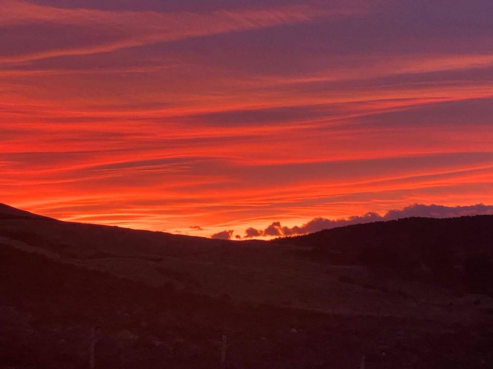 A sunset with clouds and hills in the background at Migdale Heights - Luxury Cabins in The Highlands