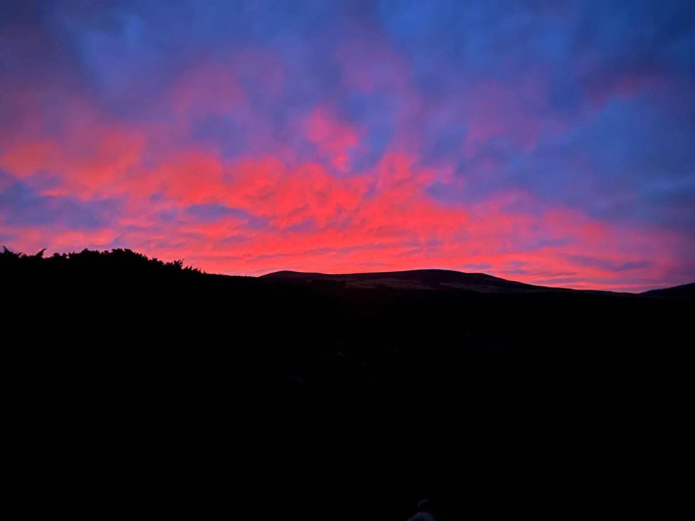 A scenic view of a sunset with clouds over mountains at Migdale Heights - Luxury Cabins in The Highlands