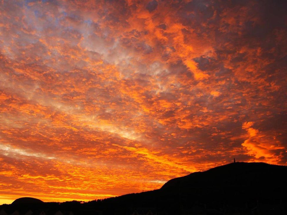 A vibrant sunset sky over a mountain at Migdale Heights - Luxury Cabins in The Highlands