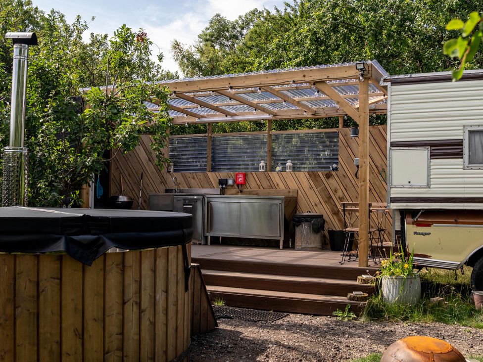 An outdoor kitchen with a hot tub near a camp trailer at 1 Bed Vehicle Luxury Camper -Hot Tub, Pets - Willy, Mill Lane Farmhouse near Burgh Le Marsh