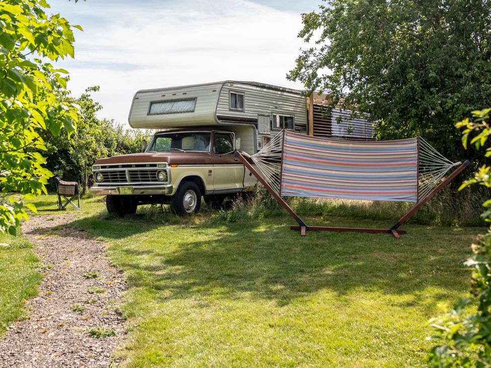 A camper with a hammock in a grassy area at 1 Bed Vehicle Luxury Camper -Hot Tub, Pets - Willy Mill Lane Farmhouse near Burgh Le Marsh