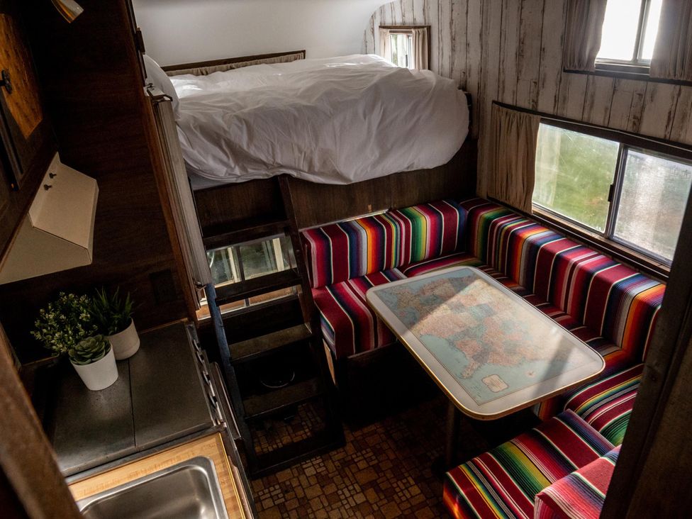A living room with a bed above a dining area at 1 Bed Vehicle Luxury Camper -Hot Tub, Pets - Willy near Mill Lane Farmhouse