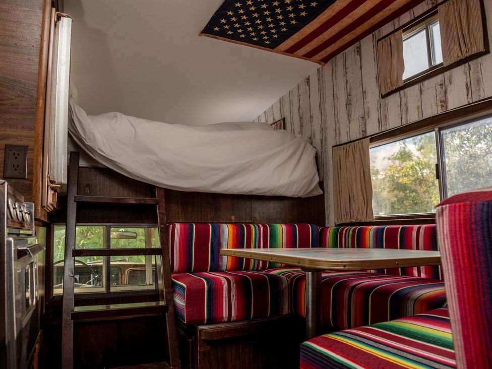 A living room with a loft bed and colorful striped seating at 1 Bed Vehicle Luxury Camper -Hot Tub, Pets - Willy, Mill Lane Farmhouse near Burgh Le Marsh