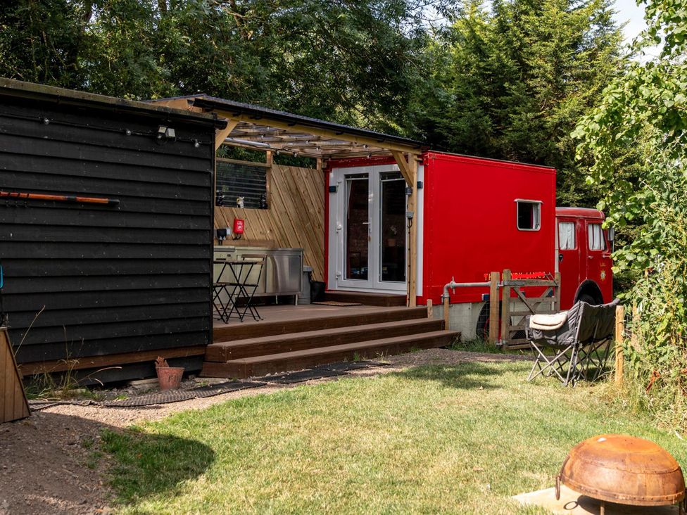 An outdoor area with a red truck and deck at Sleeps 2 -Private Garden -Pets Ok -Hot Tub -Dennis