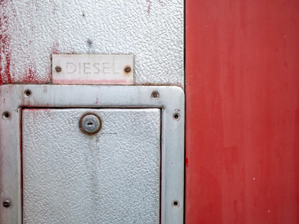 A diesel fuel access lid on a red surface