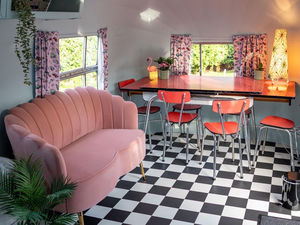 A dining room with a pink sofa and a table at Sleeps 2 - Hot Tub - Pet Friendly - PeggySue