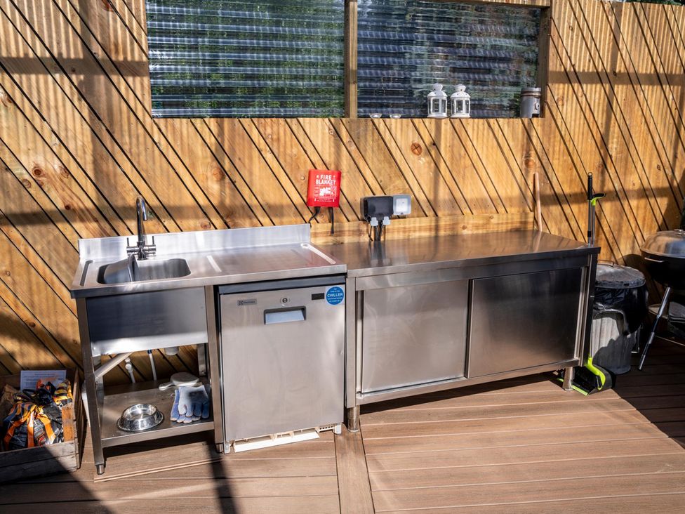 An outdoor kitchen with a sink, refrigerator, and grill at Sleeps 2 - Hot Tub - Pet Friendly - PeggySue