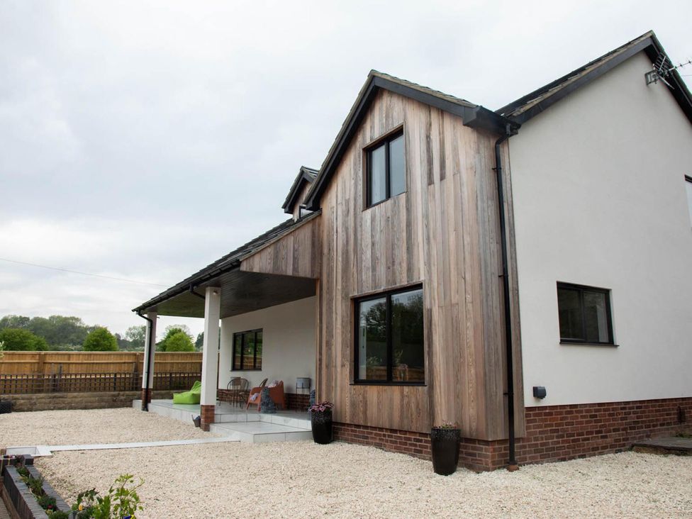 An outdoor view of a house with a wooden porch at House Sleeps 10 with Enclosed Garden