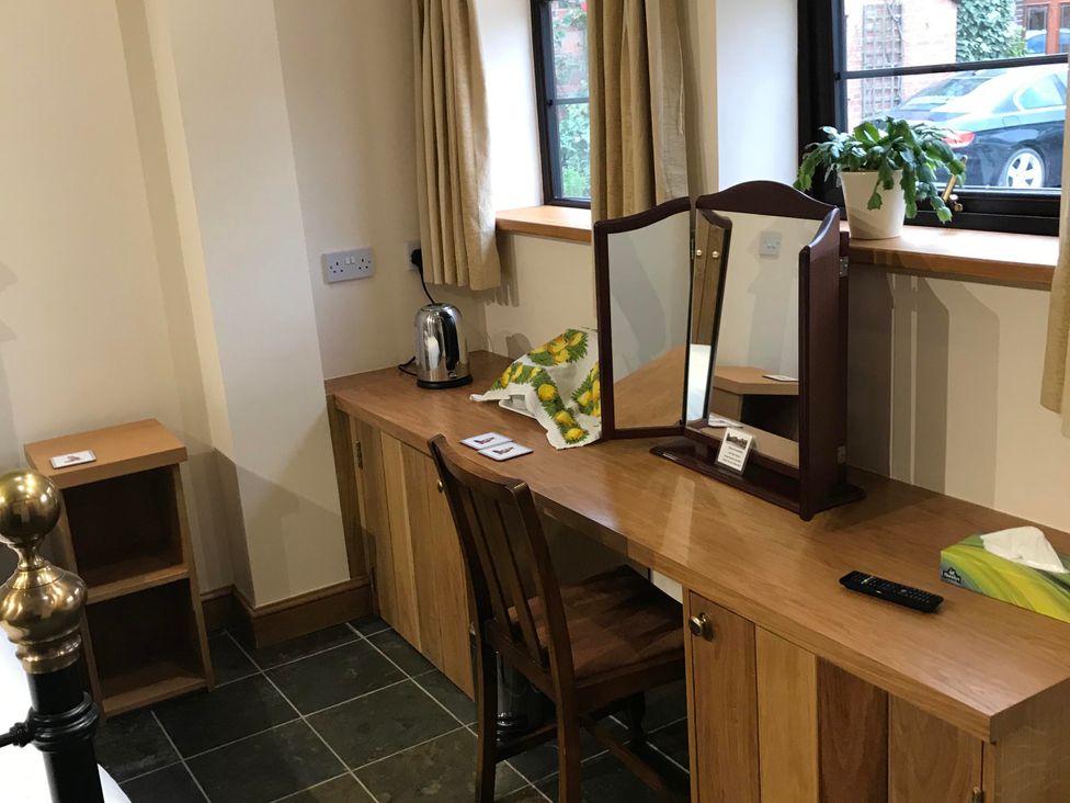 A bedroom with a table and chair along with a kettle and mirror