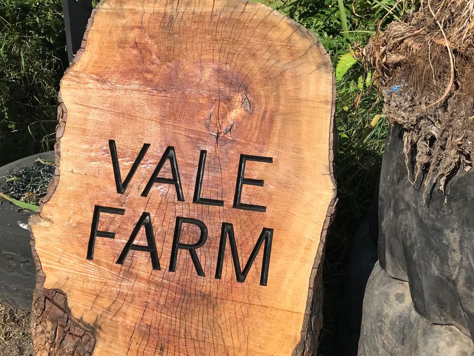 A wooden sign with the text 'VALE FARM' in an outdoor area