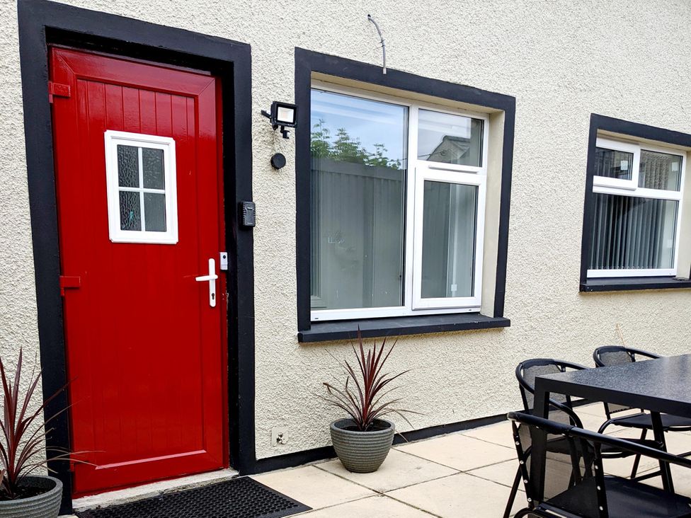 An outdoor area with a red door, windows, and a dining table at the property