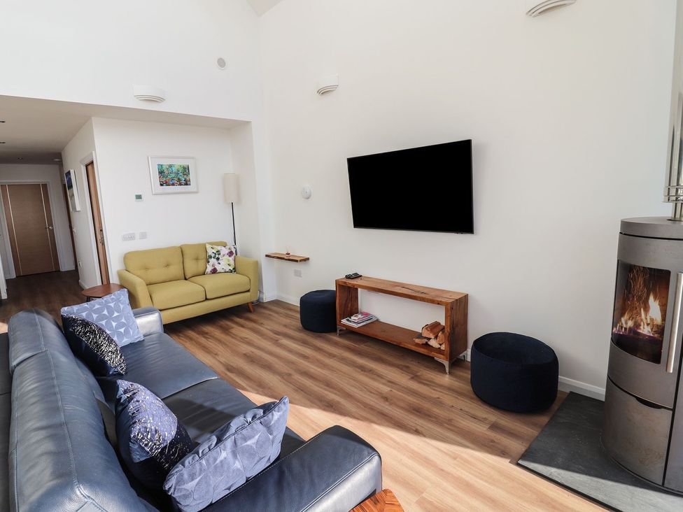 A living room with a sofa, chair, television, and fireplace at 8B Carrigreich Isle of Harris