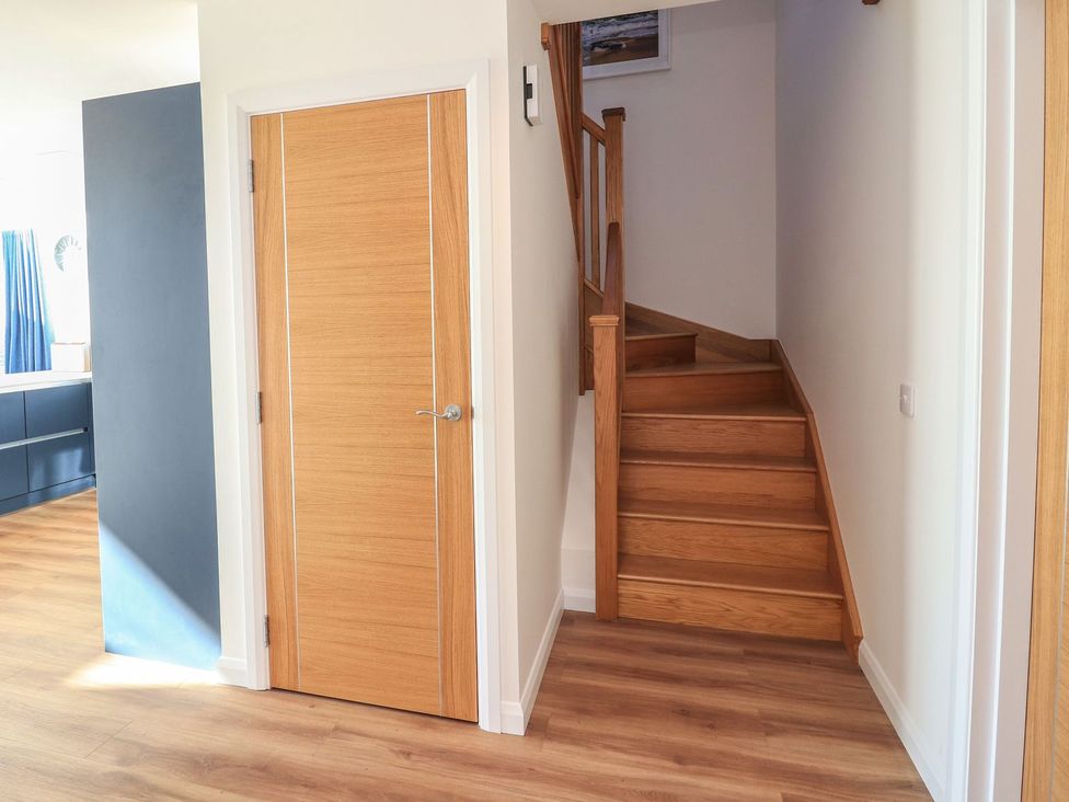 A hallway with a staircase and door at 8B Carrigreich in Isle of Harris