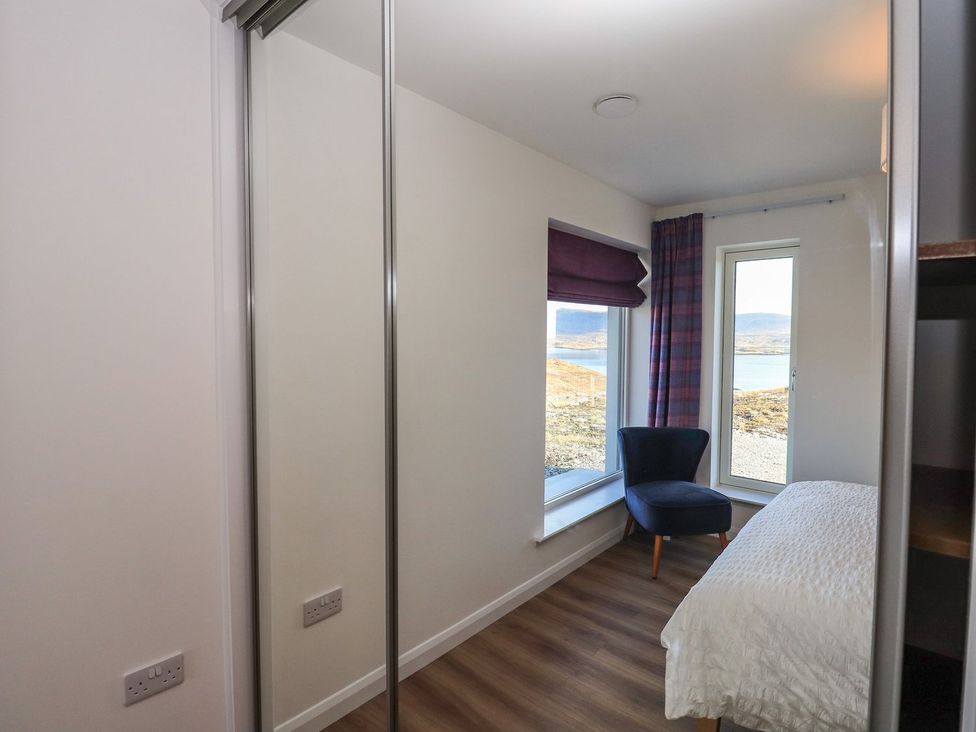 A bedroom with a bed and a chair at 8B Carrigreich on Isle of Harris