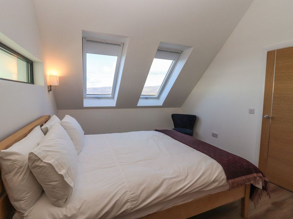 A bedroom with a bed and windows at 8B Carrigreich Isle of Harris
