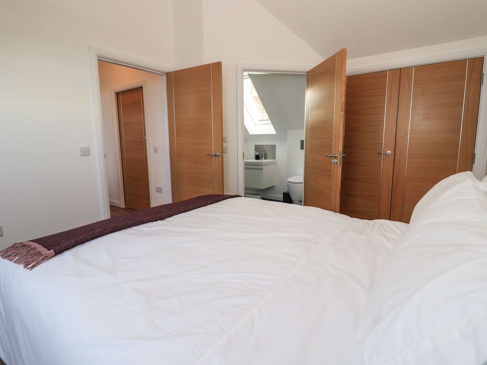 A bedroom with a bed and open doors leading to a bathroom at 8B Carrigreich, Isle of Harris