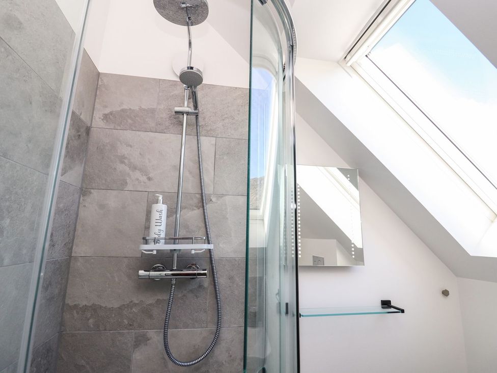 A shower area with wall tiles and a glass shelf at 8B Carrigreich Isle of Harris