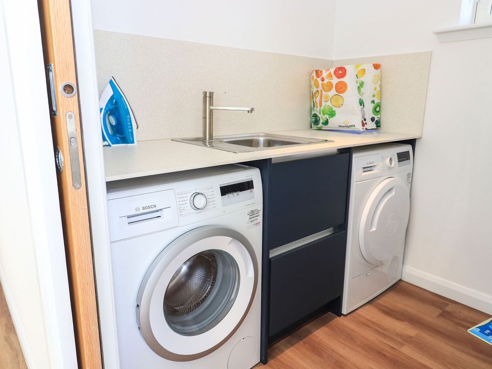 A laundry room with washing machine, dryer, and sink at 8B Carrigreich in Isle of Harris