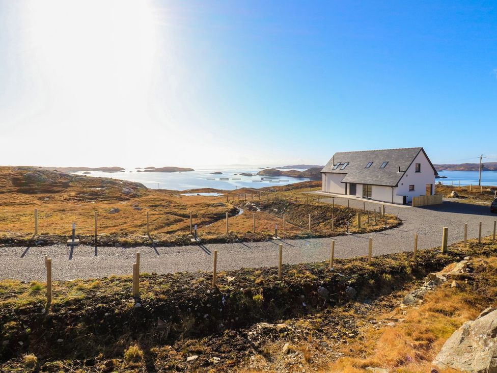 A house by the water with a gravel road and a fence at 8B Carrigreich Isle of Harris