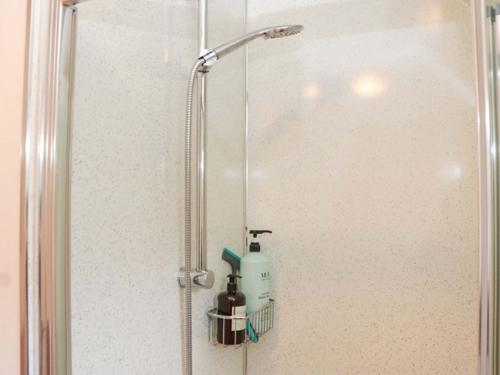A shower with a shower head and soap dispenser at Halsdon Avenue in Exmouth