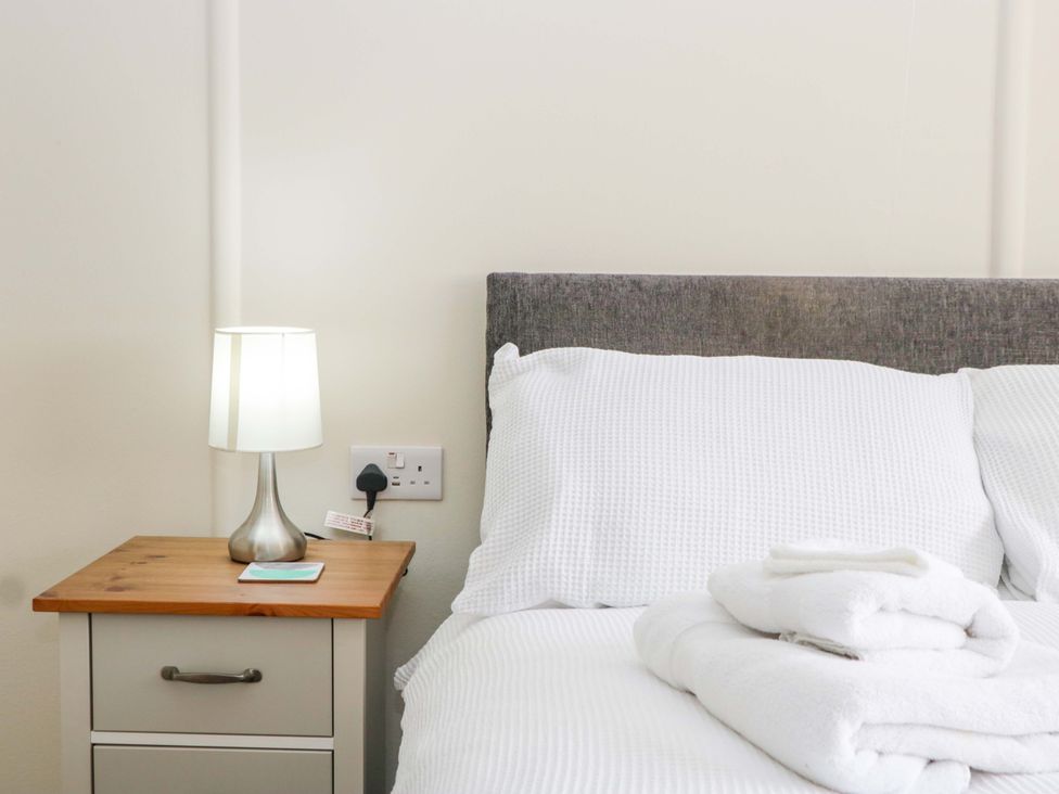 A bedroom with a bed, lamp, and nightstand at Halsdon Avenue Exmouth