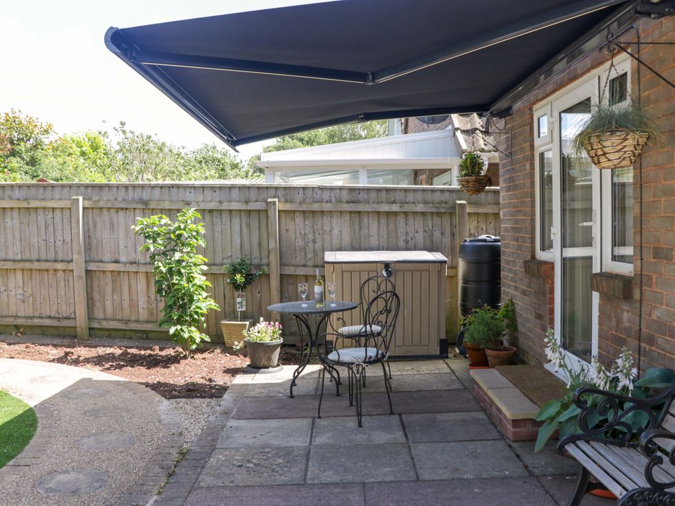 A garden with a table and chairs under an awning at Halsdon Avenue Exmouth