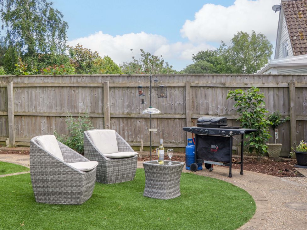 A garden with two chairs, a table, and a barbecue grill at Halsdon Avenue in Exmouth
