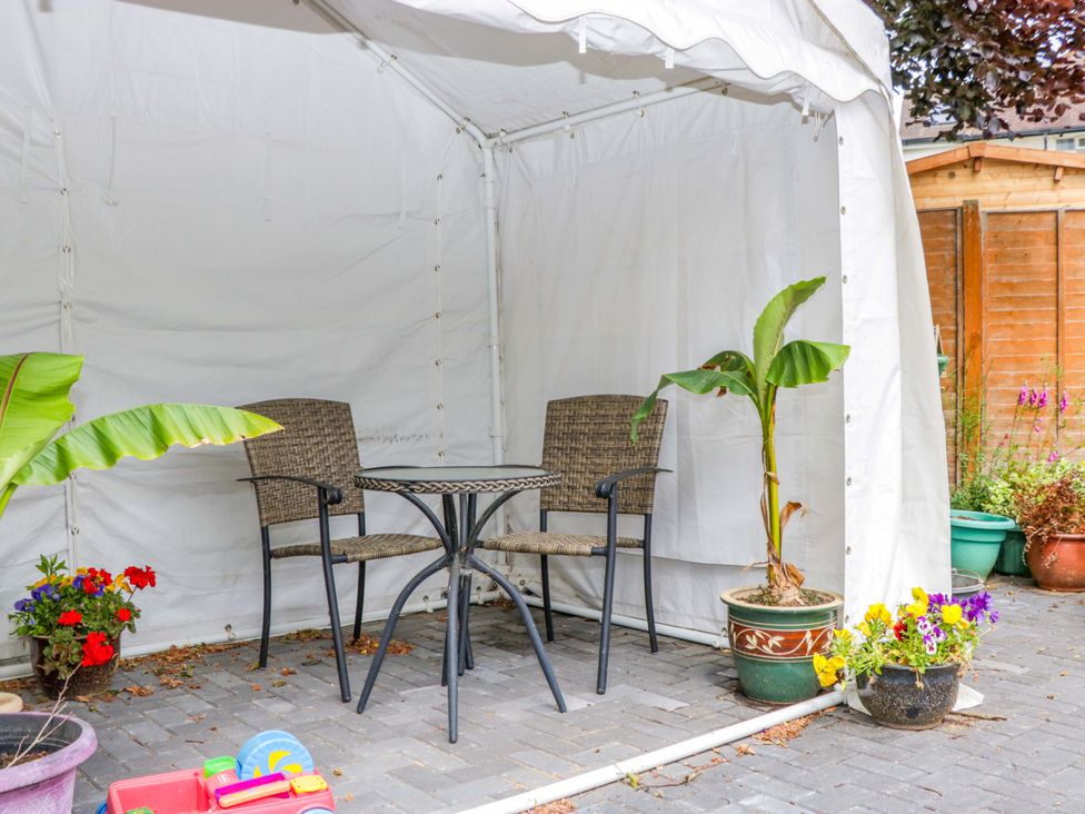 An outdoor area with a table and chairs under a tent at Halsdon Avenue in Exmouth