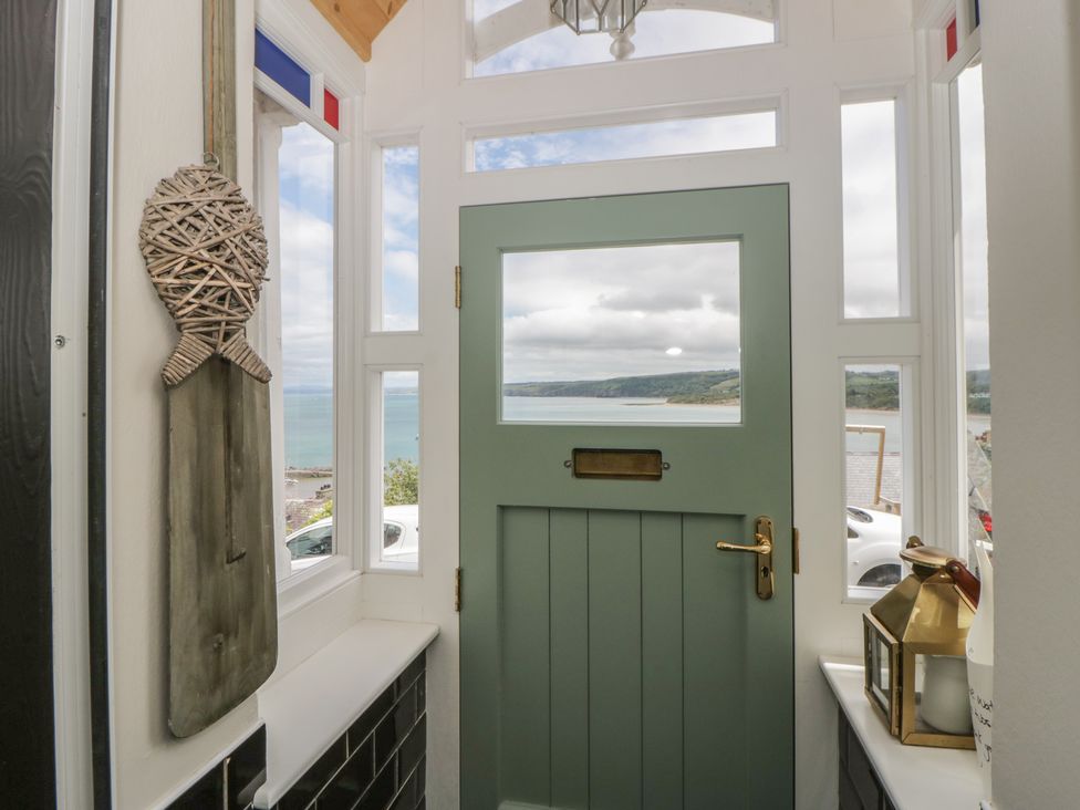 A hallway with a green door and windows overlooking the sea at Arosfa New Quay