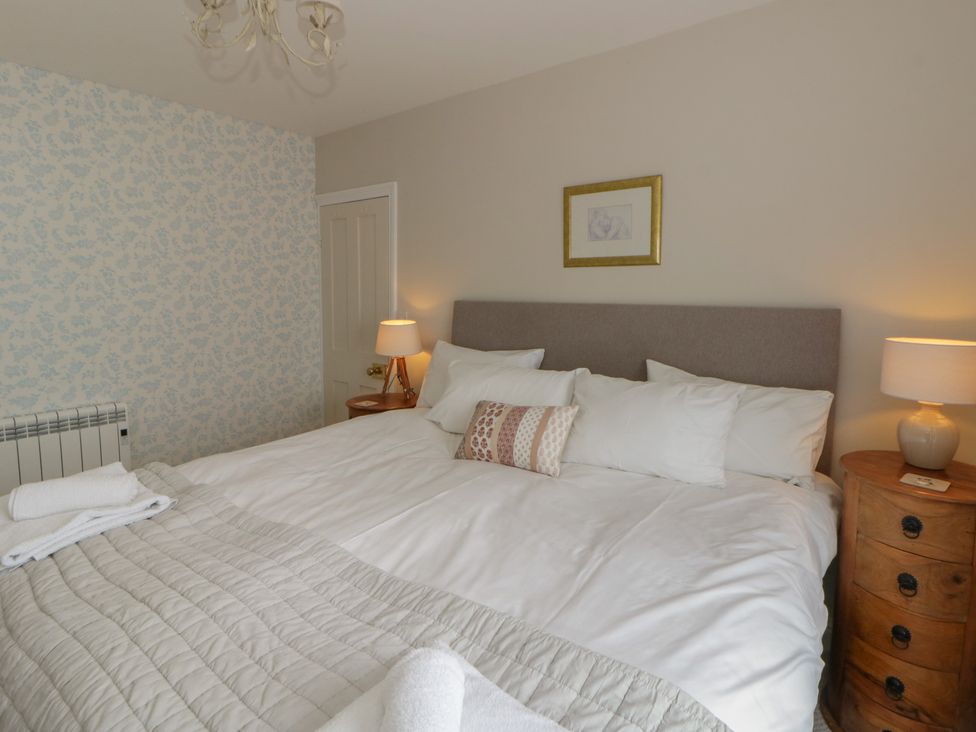 A bedroom with a bed and bedside lamps at Arosfa New Quay