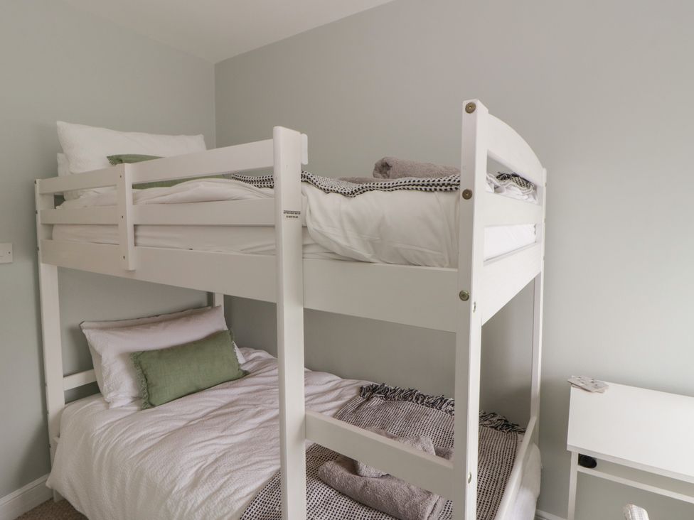 A bedroom with a bunk bed and bedding at Arosfa New Quay