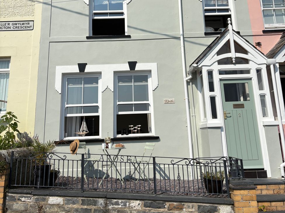 An outdoor area with a table and chair in front of a house at Arosfa in New Quay