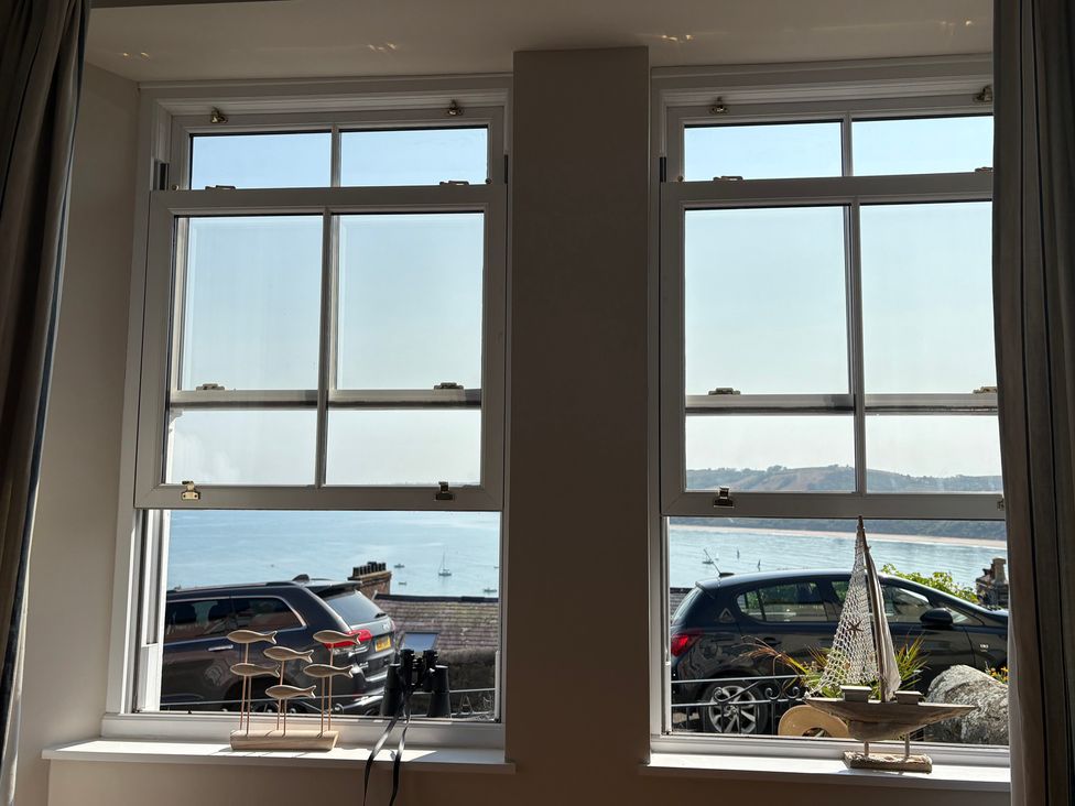Two windows with ocean view and decorative items in a living room at Arosfa New Quay