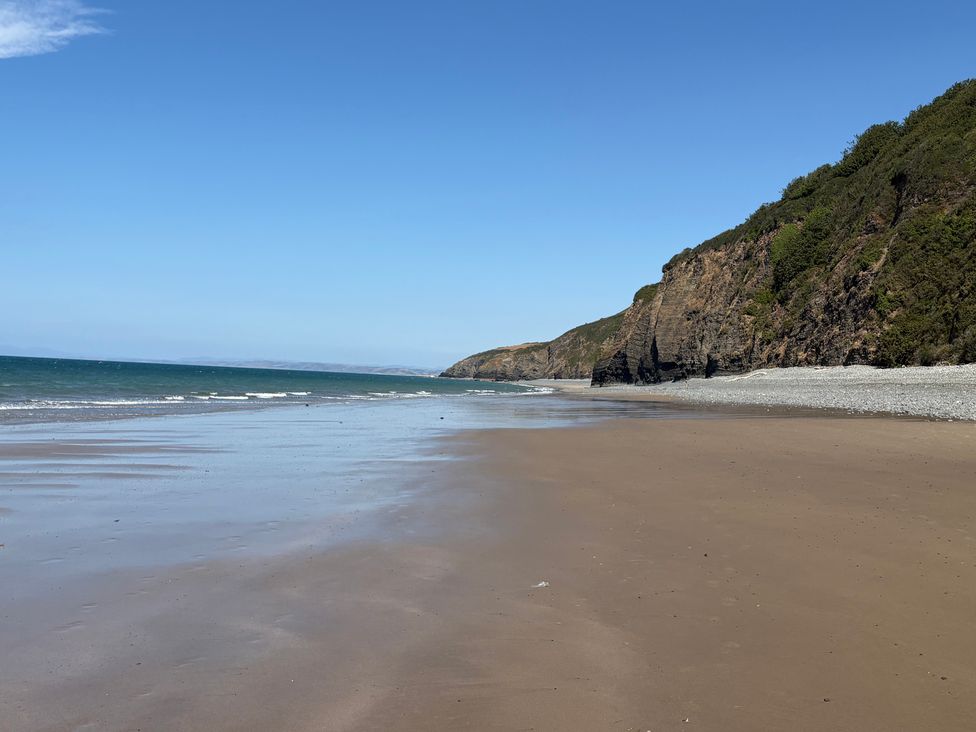 A beach with sand and cliffs near the sea at Arosfa New Quay