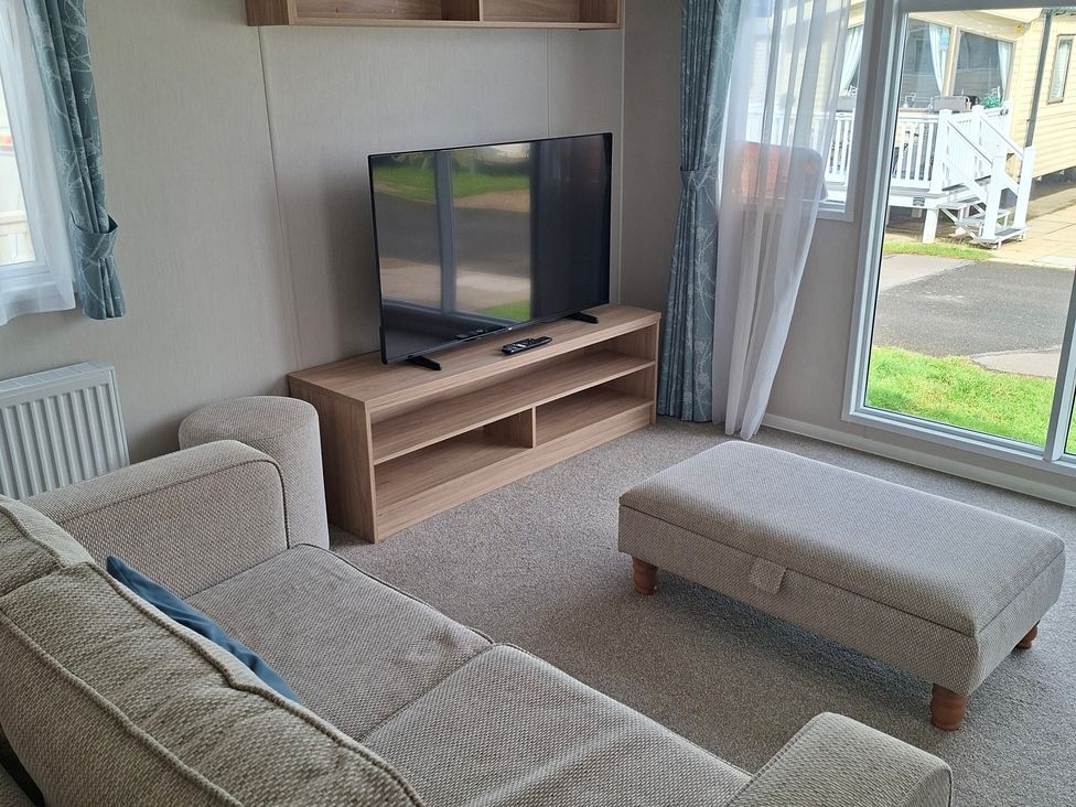 A living room with a sofa and television at Primrose Valley, Amara's Retreat, Filey