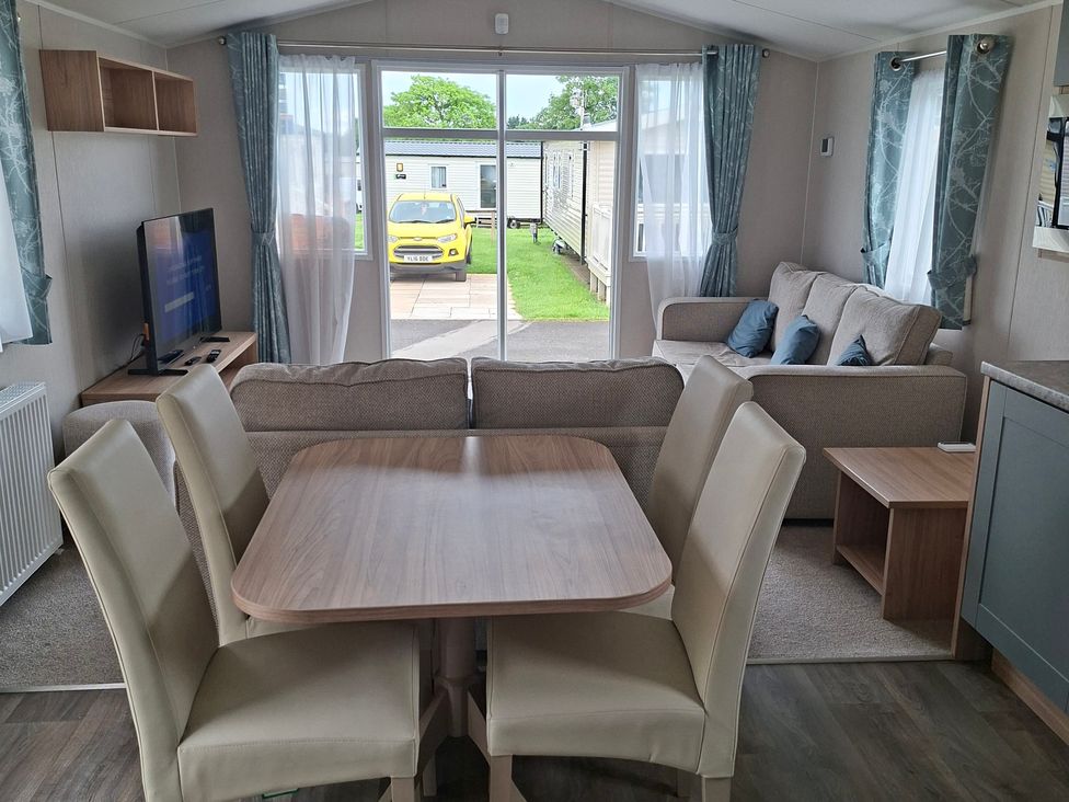 A living room with a dining area and a view outside at Primrose Valley, Amara's Retreat, Filey