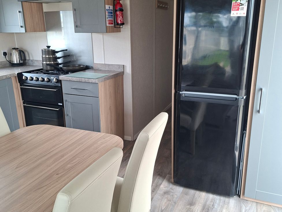A kitchen with a stovetop and black fridge at Primrose Valley, Amara's Retreat in Filey
