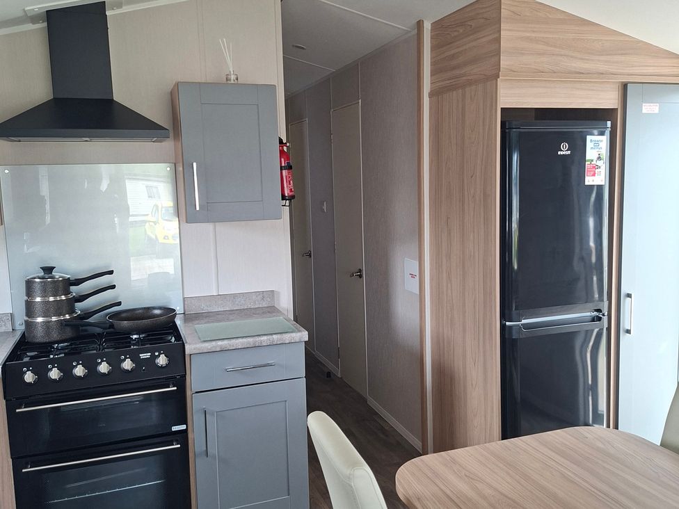 A kitchen with stove and refrigerator at Primrose Valley, Amara's Retreat in Filey